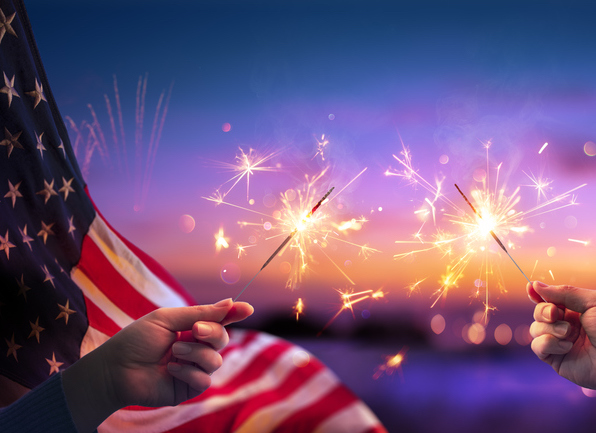 two little kids holding sparklers with american flag in background