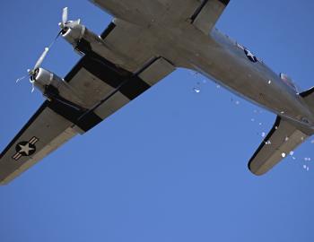 Candy parachutes float to waiting children as the Candy Bomber flies overhead.