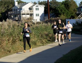 Runners competing in the 2019 Outer Banks Marathon run past Kitty Hawk Bay.