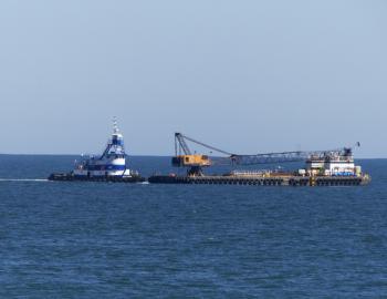 A barge is maneuvered into position to pump sand onto an Outer Banks Beach.