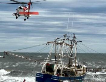 Coast Guard helicopter pulls on of the four crewmen from Bald Eagle II.