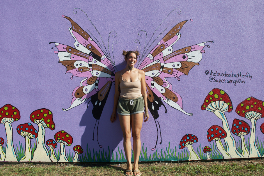 Artist Kennedy Fletcher stand amidst one of her butterfly murals.