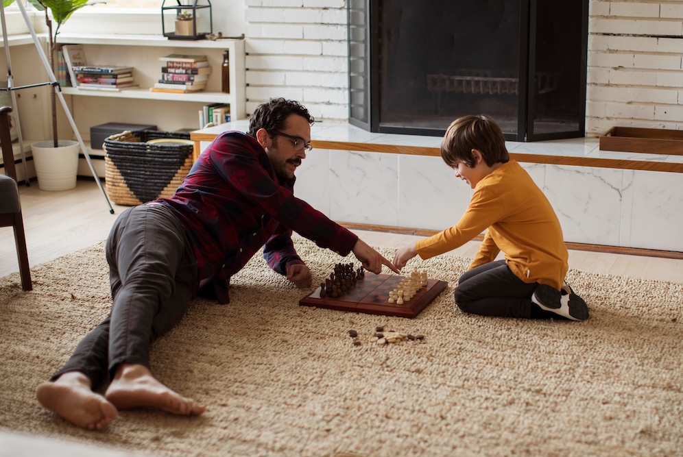 father and son playing chess inside