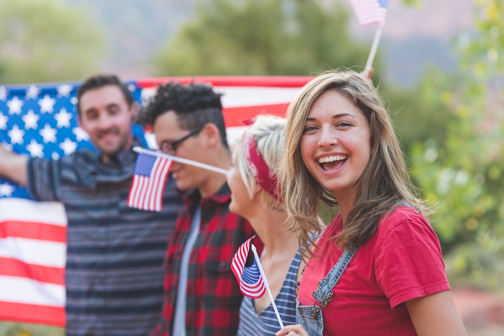 friends in red, white, and blue holding American flags on the 4th of July