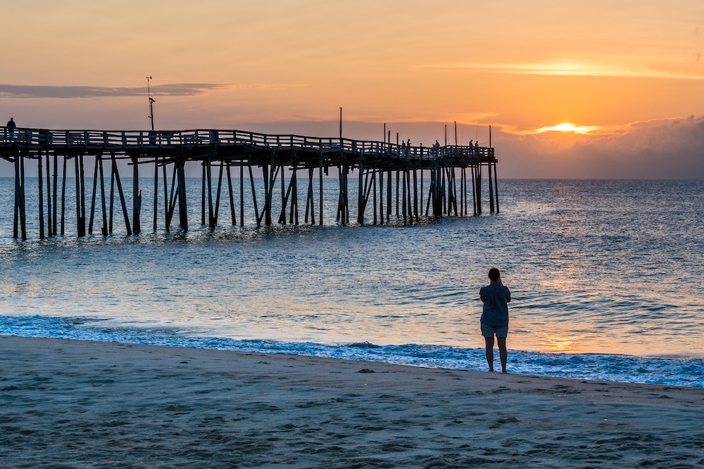woman standing on beach on Outer Banks near fishing pier