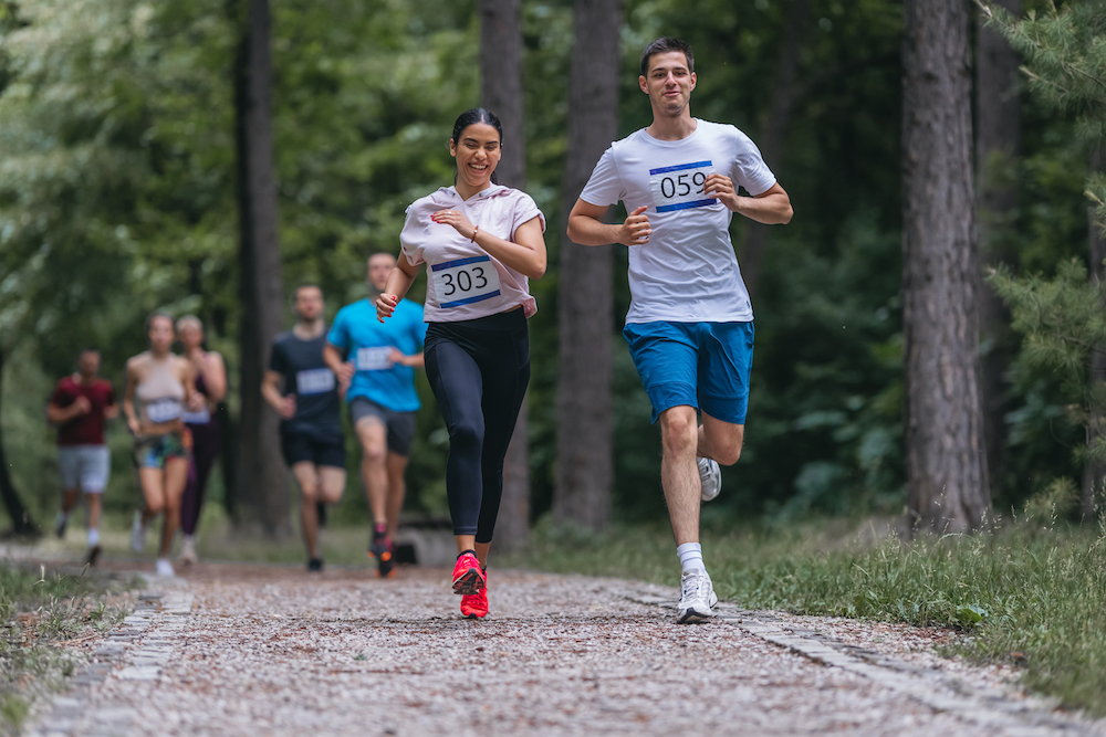 marathon runners jogging along a wooded trail