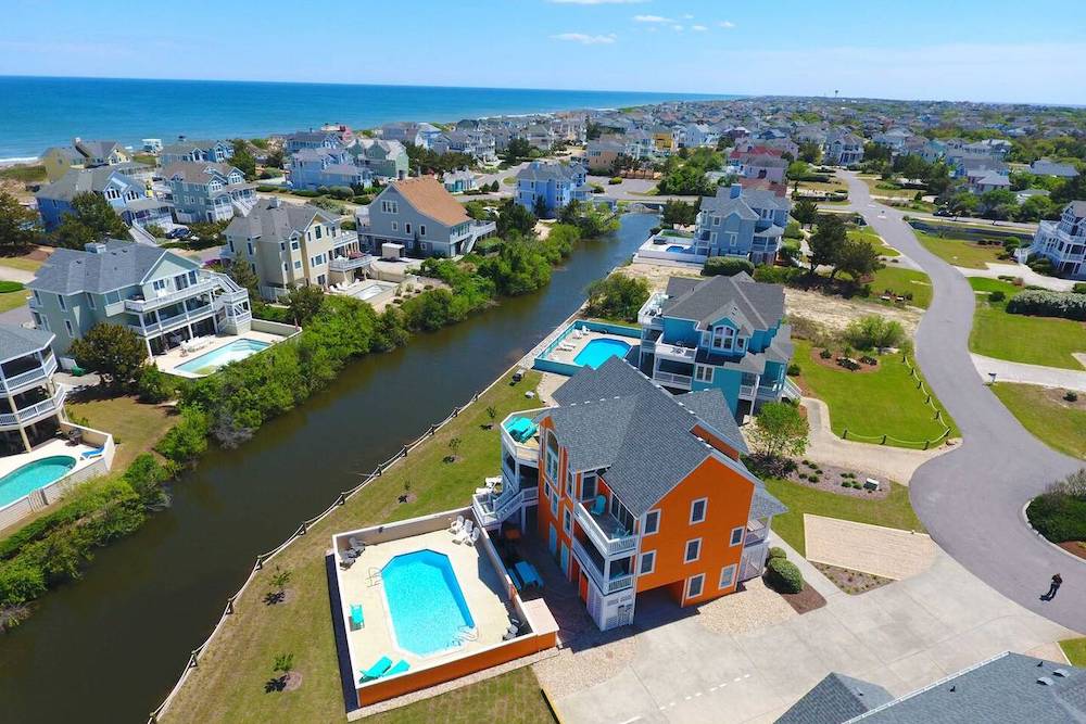 aerial view of outer banks home showing canal and in-ground pool